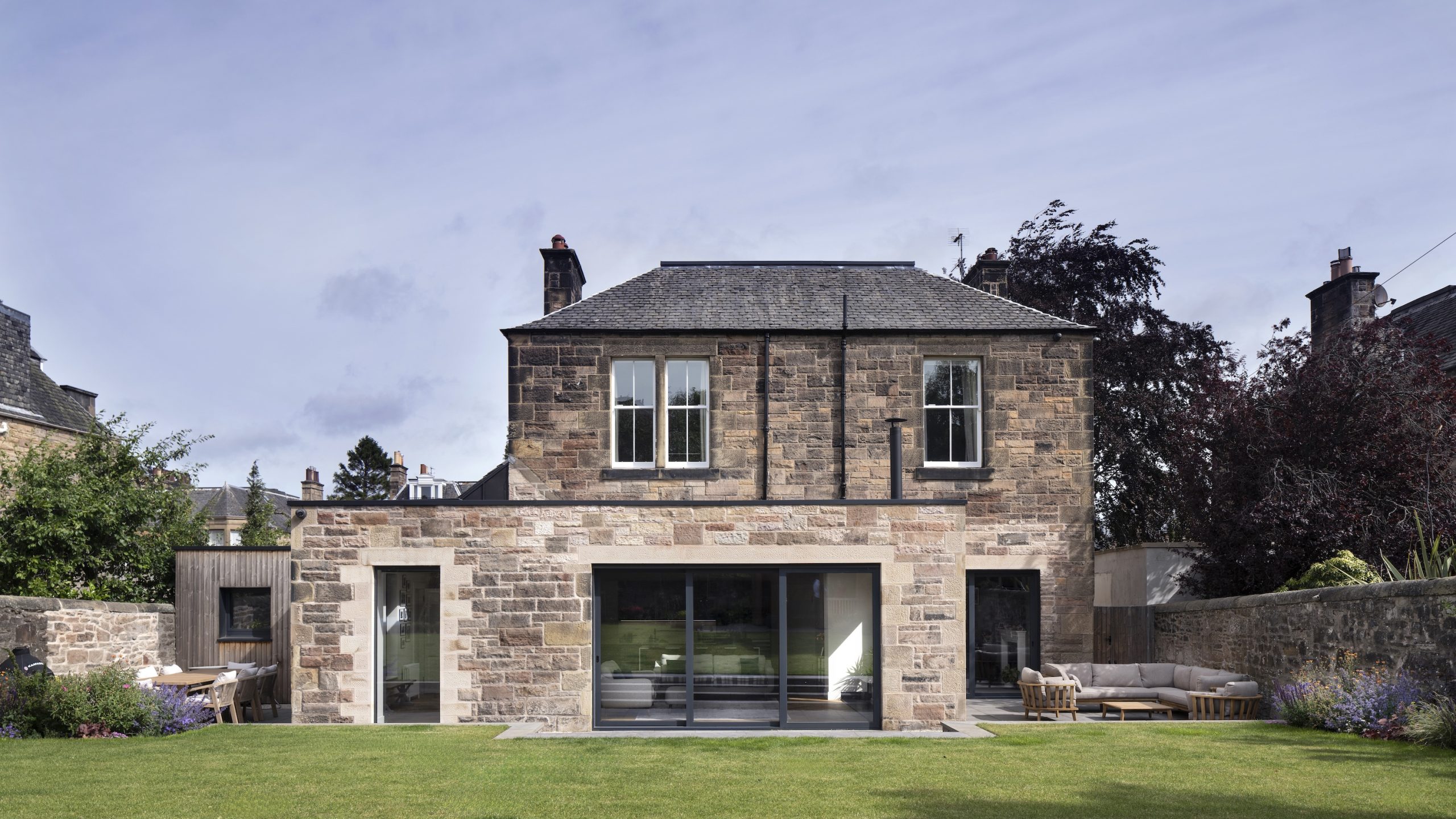 Sandstone extension with large glazing facing garden