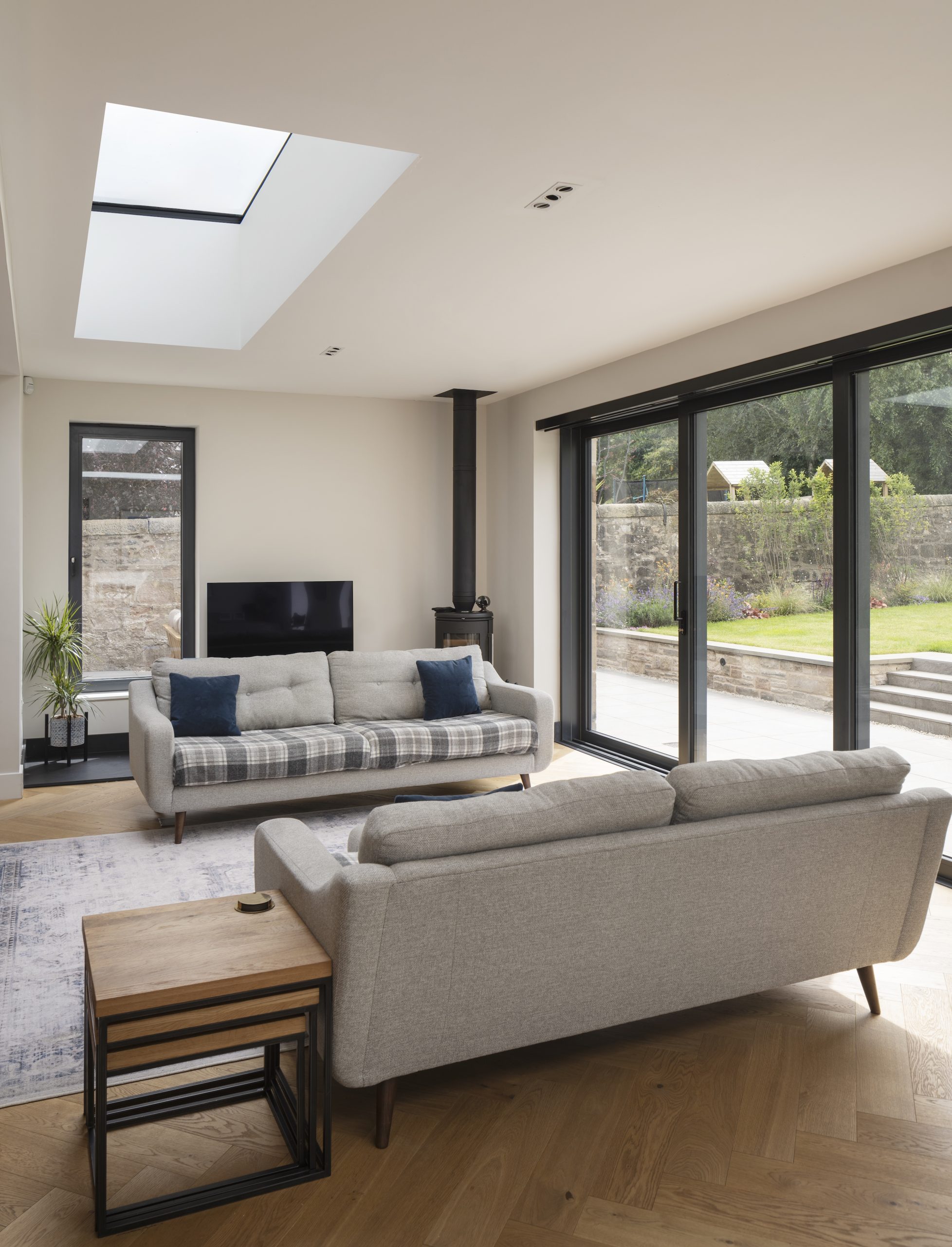 Living room with wood burning stove large glazing and frameless rooflight