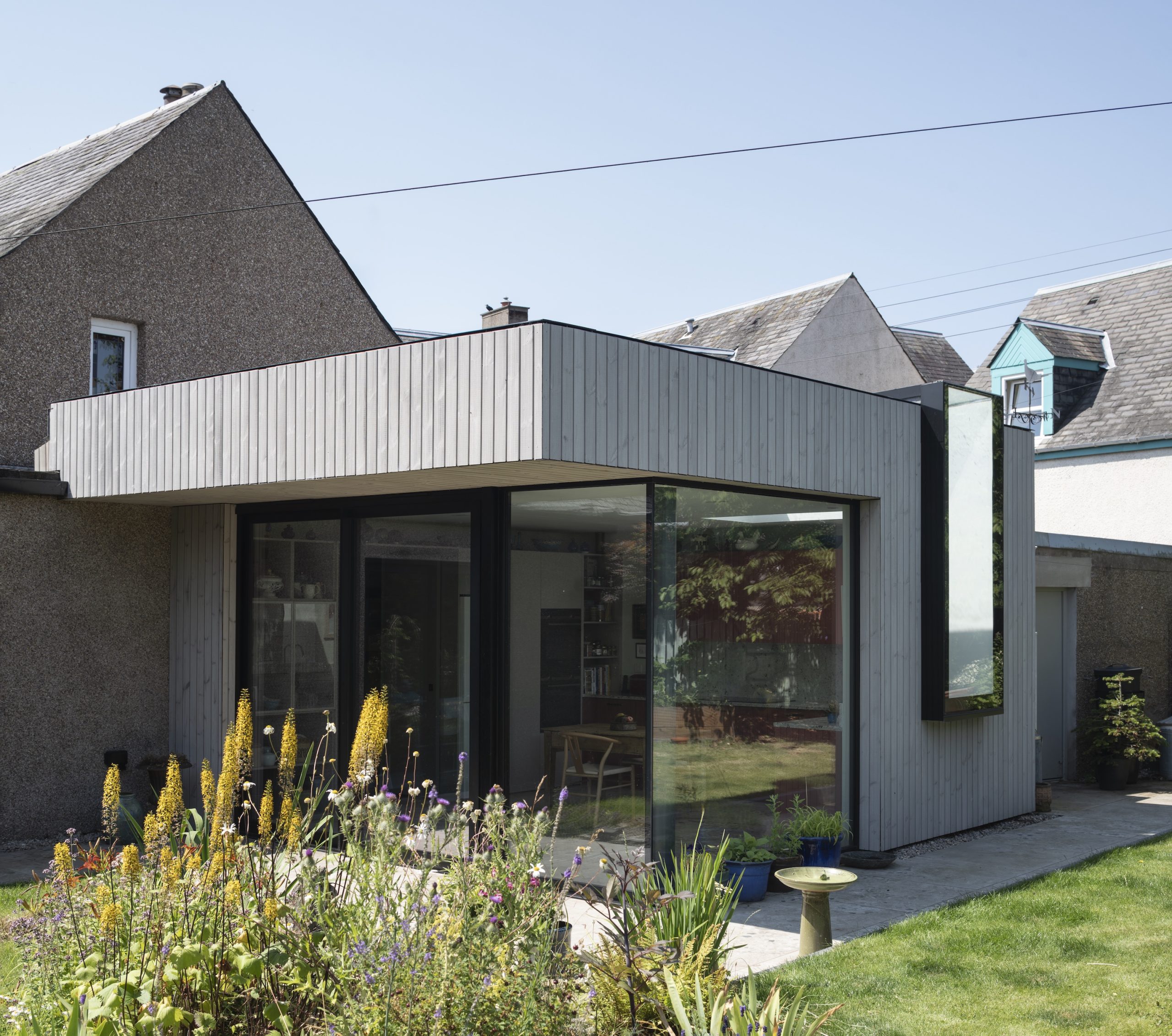 Timber clad extension with frameless corner glazing and frameless window and rooflight