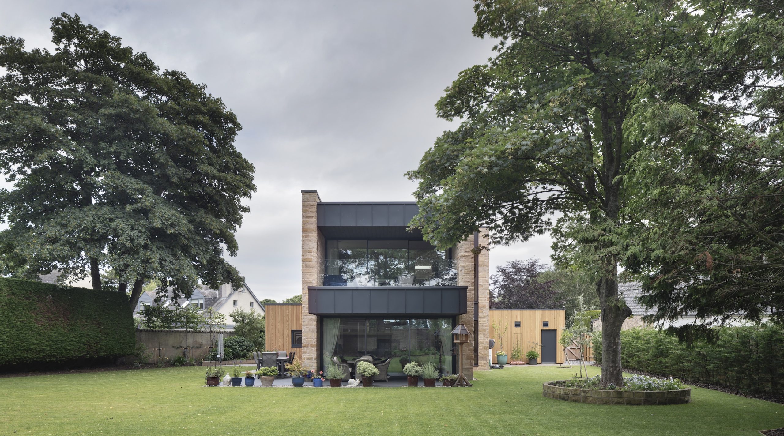 Sandstone villa with large zinc clad balcony and terrace in garden setting