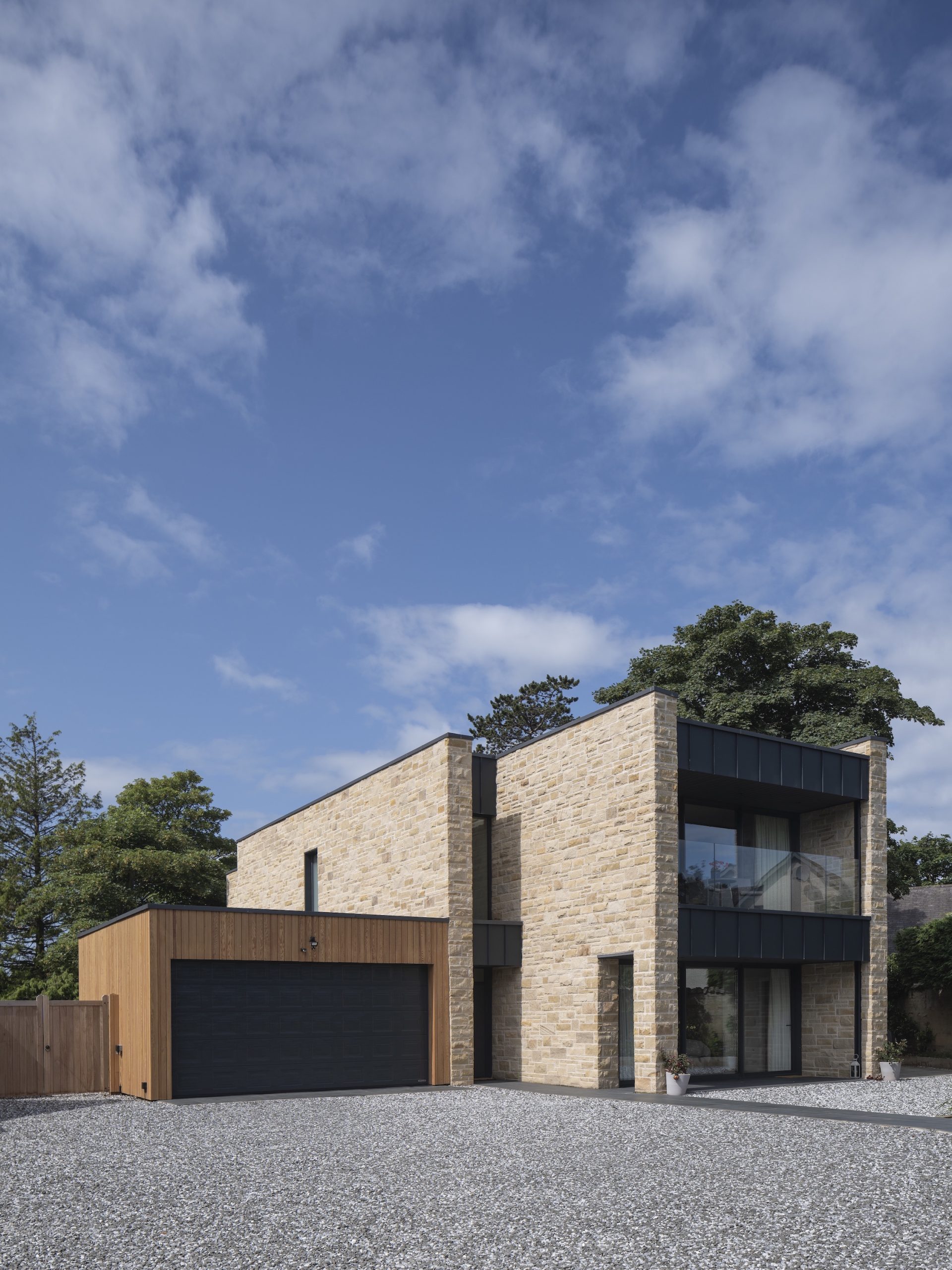 Sandstone villa with large zinc clad balcony and terrace in garden setting