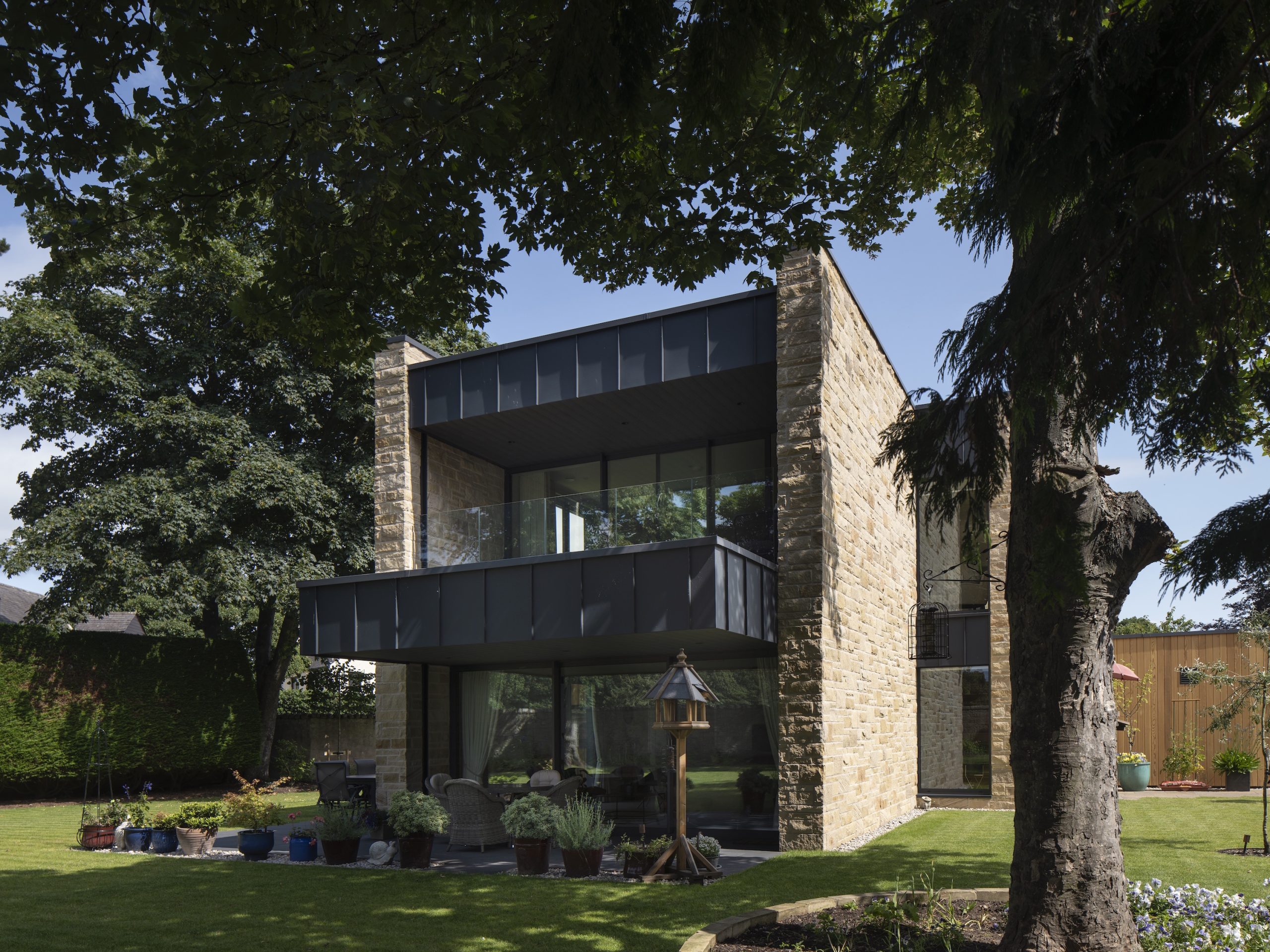 Sandstone villa with large zinc clad balcony and terrace in garden setting