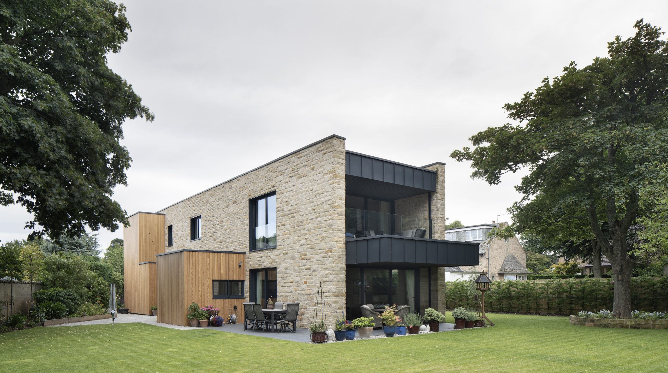 Sandstone villa with large zinc clad balcony and terrace in garden setting