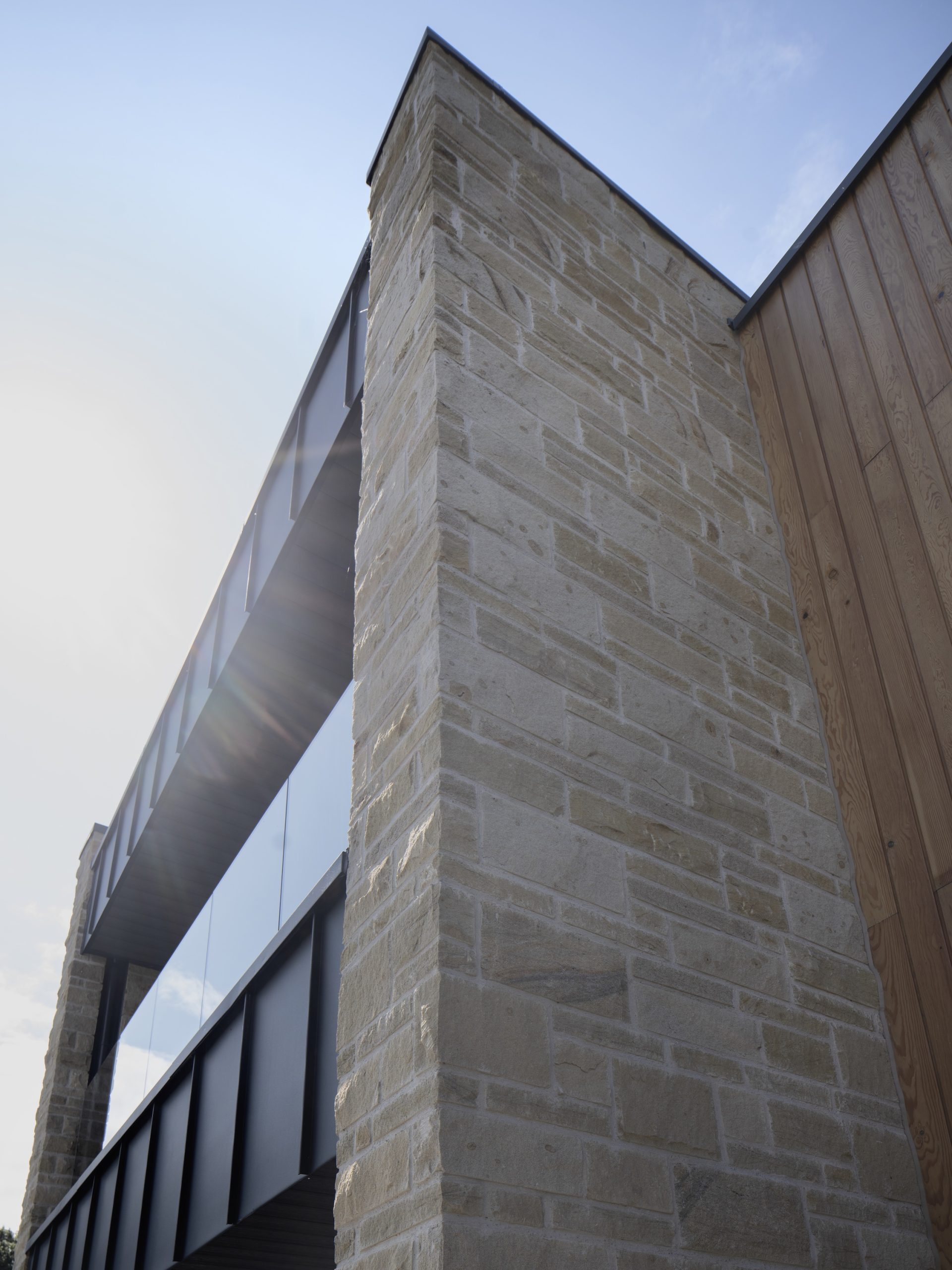 Sandstone villa with zinc clad balcony and frameless glass barrier