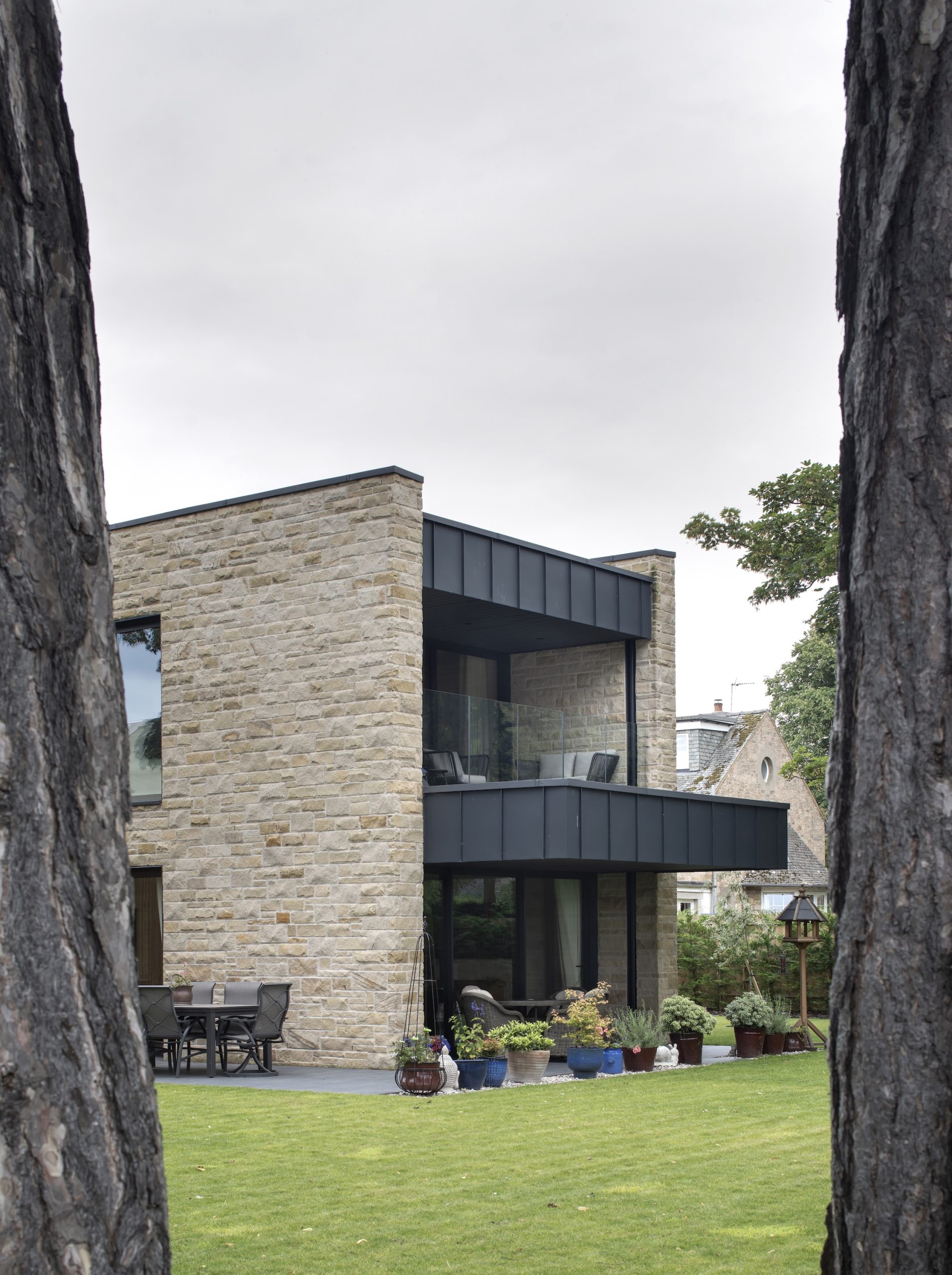Sandstone villa with large zinc clad balcony and terrace in garden setting