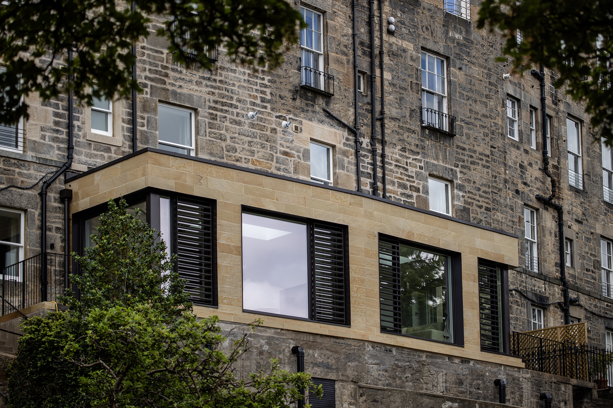 Contemporary sandstone extension with large glazing with bronze coloured louvres