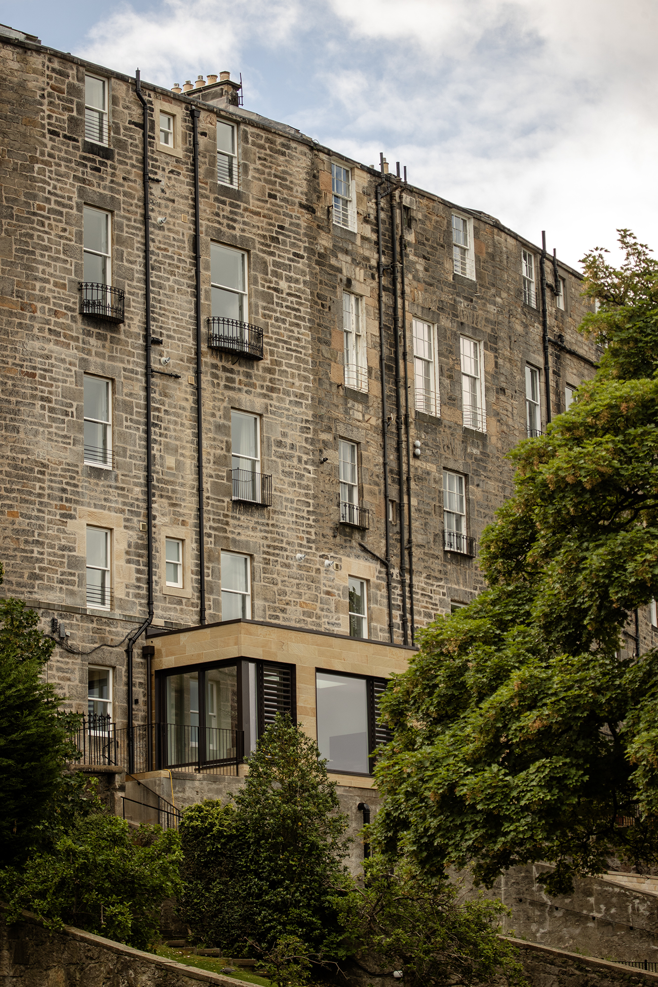 Contemporary sandstone extension with large glazing with bronze coloured louvres