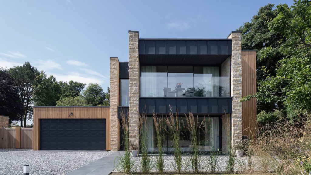 Sandstone villa with large zinc clad balcony and terrace in garden setting