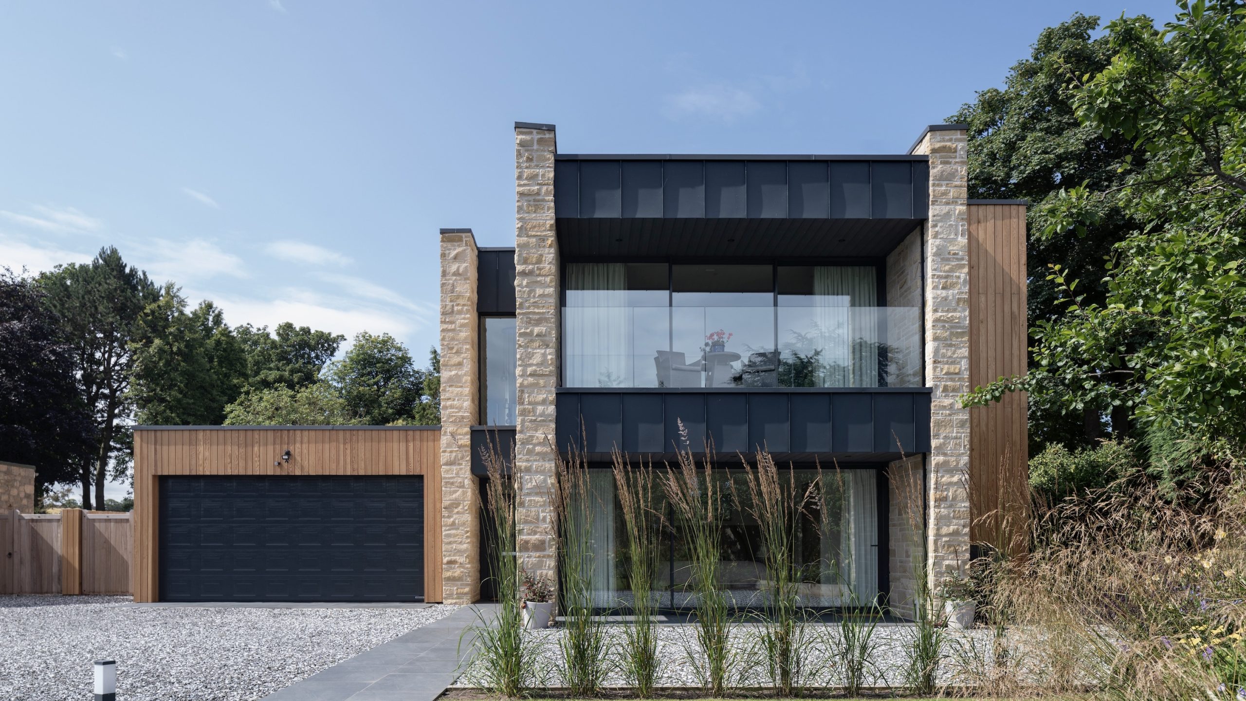 Sandstone villa with large zinc clad balcony and terrace in garden setting